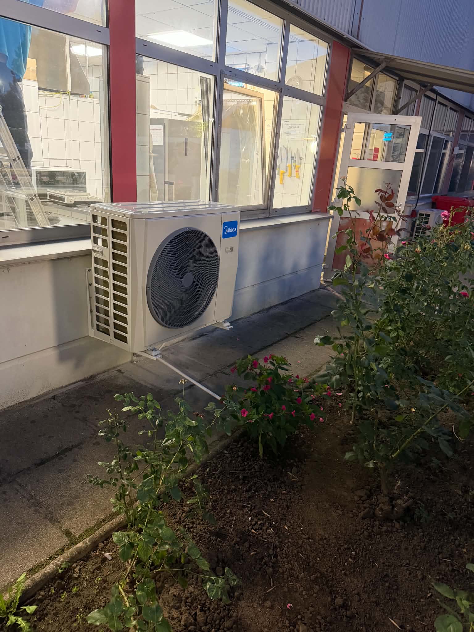 Kültéri klímaegység egy nagy üvegablakokkal rendelkező épület falánál