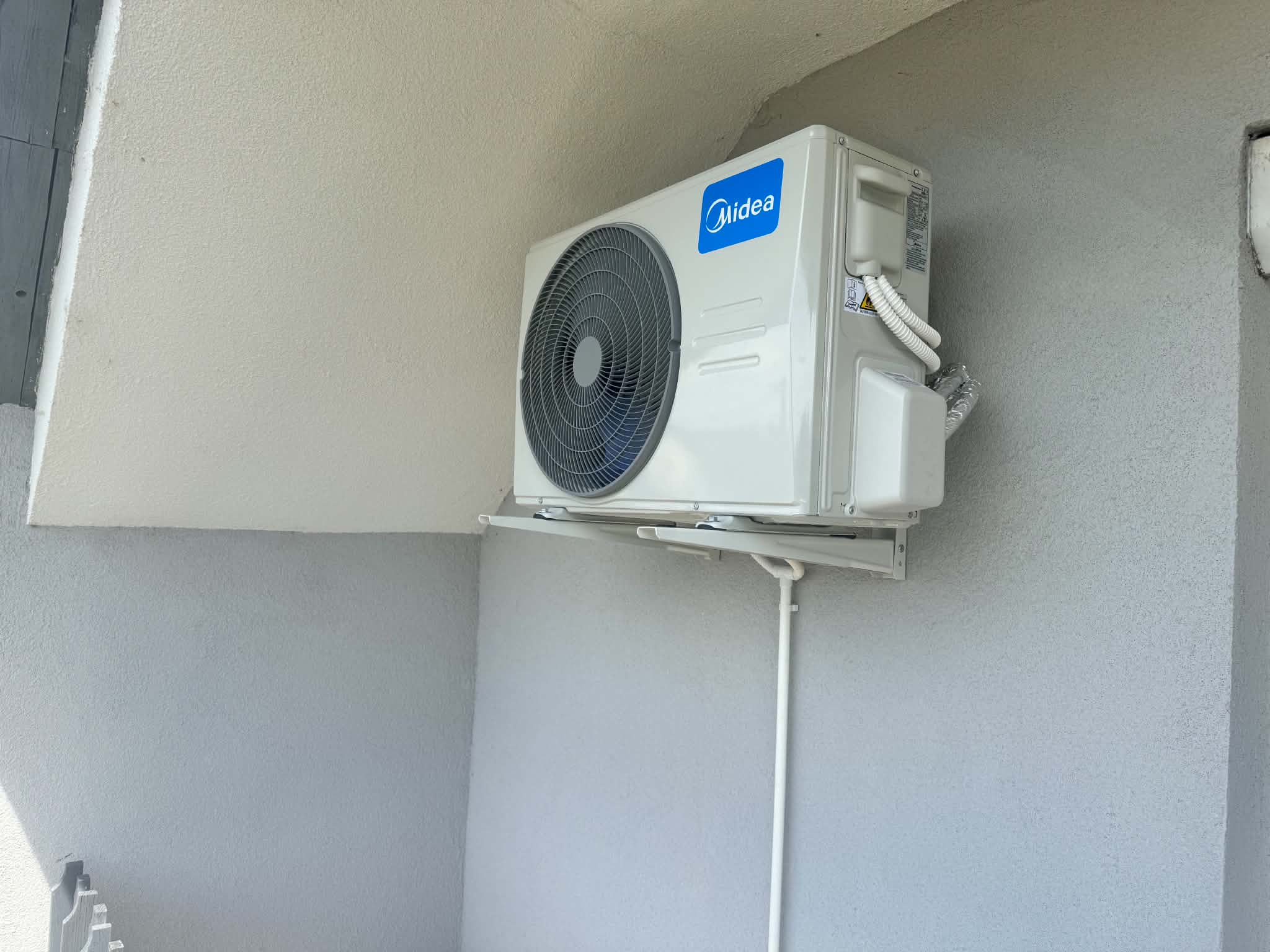 Midea kültéri klímaegység egy világos homlokzat mélyedésében