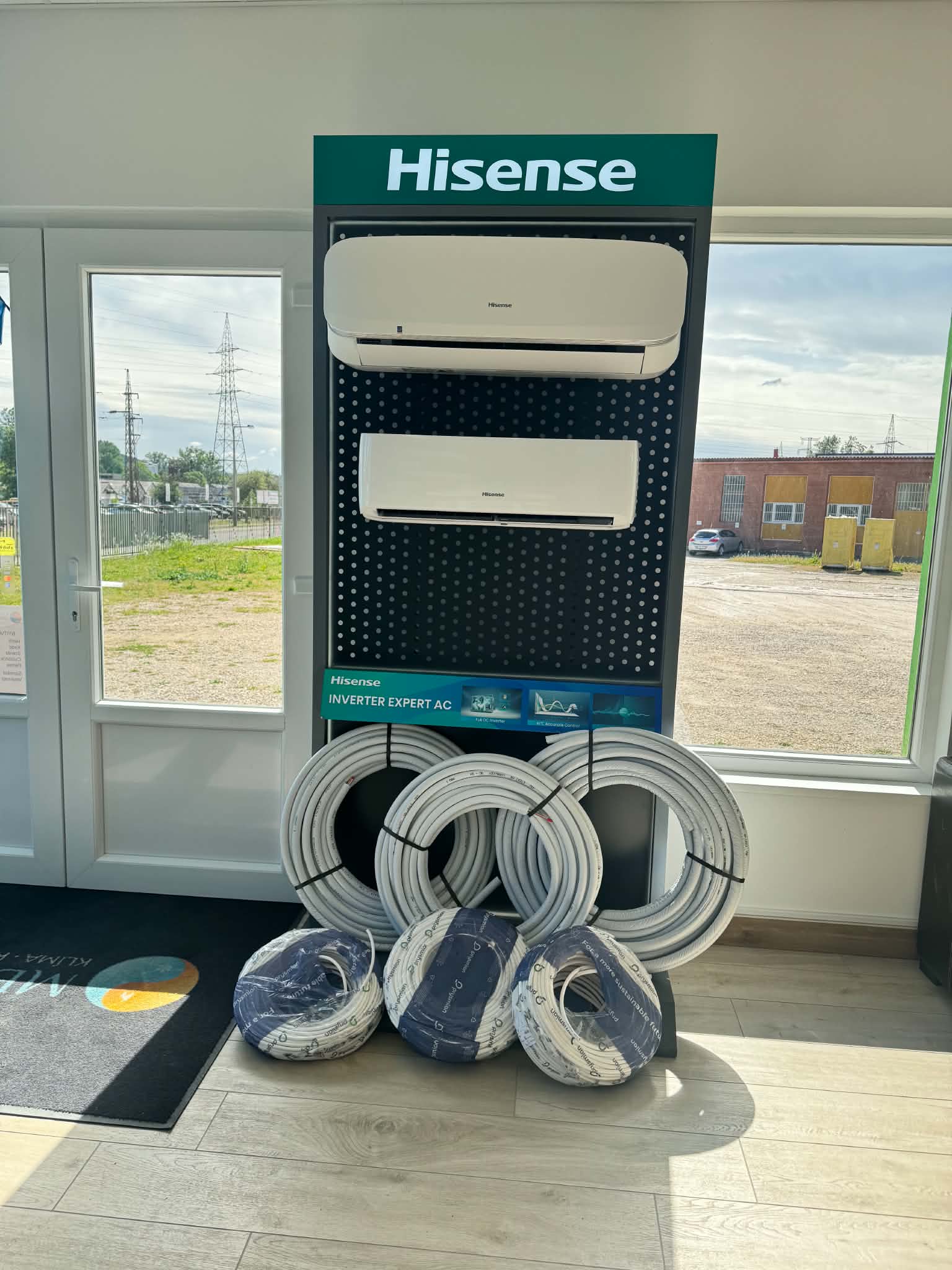 Hisense beltéri egységek egy bemutatóállványon, előttük csőtekercsekkel